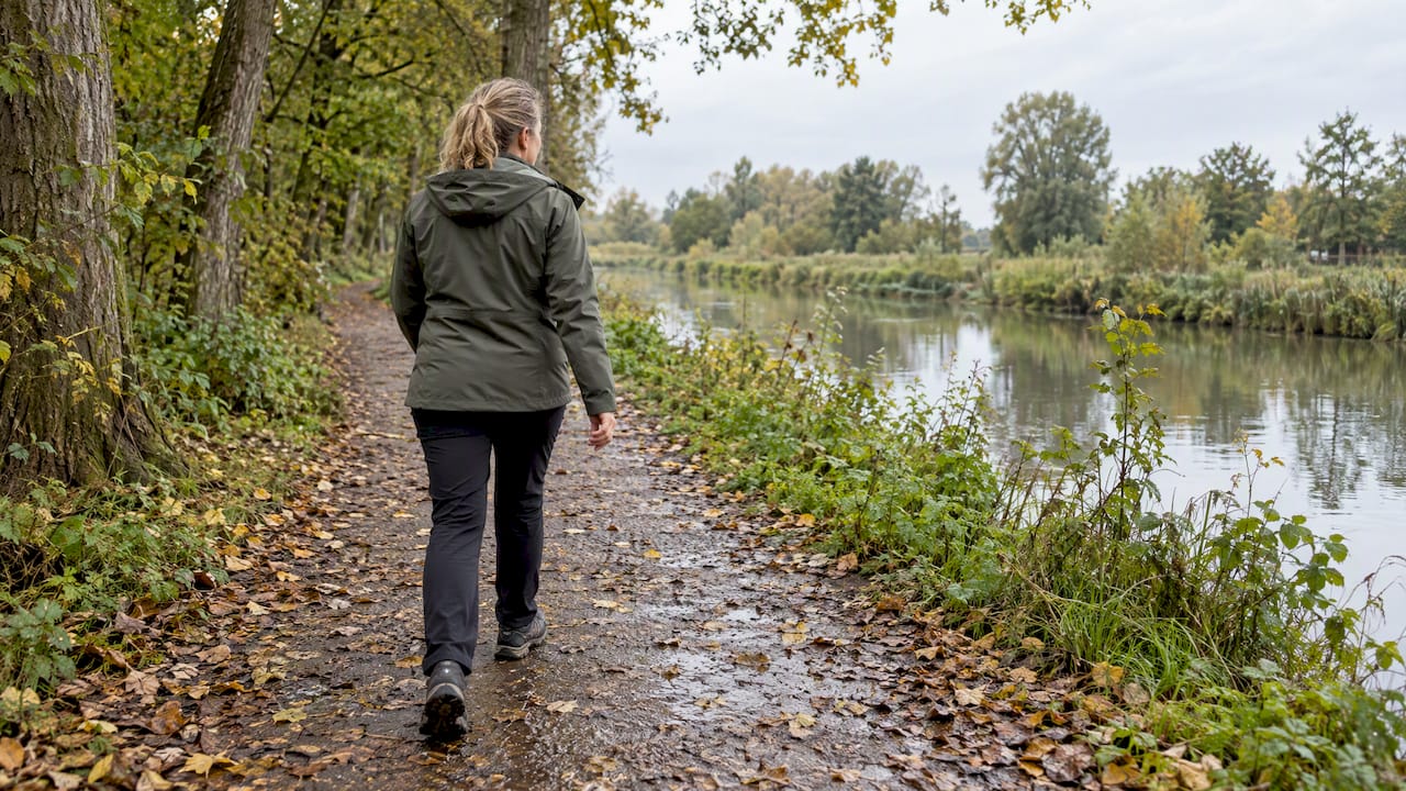 Vrouw maakt een stevige wandeling langs het groene water